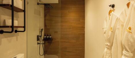 Un baño moderno con ducha envuelta en vidrio, paneles de madera en la pared y toallas blancas en un estante.