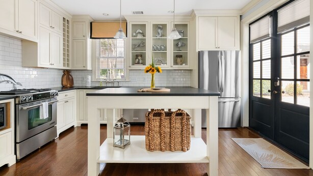A kitchen with white cabinets, a black countertop, and a built-in oven. - Picture Perfect Charleston Living on Spring St (Charleston)