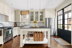 A kitchen with white cabinets, a black countertop, and a built-in oven. - Picture Perfect Charleston Living on Spring St (Charleston)