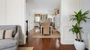 A hallway with a dining area featuring a table and chairs, a potted plant, and a sofa. - Picture Perfect Charleston Living on Spring St (Charleston)