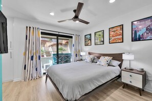 A modern bedroom with a bed, nightstand, ceiling fan, and artwork on the walls. - Atomic Starburst – Mountain View Downtown Condo (Palm Springs)