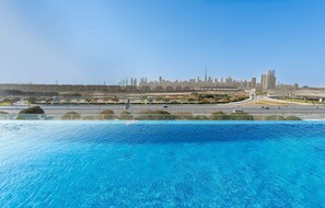 A swimming pool with a city skyline in the background. - Stayshort - Luxury 3BR Apartment in Meydan That Sleeps 5 (Dubai)