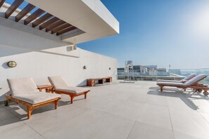 A rooftop lounge with sun loungers and a view of the cityscape. - Stayshort - Luxury 3BR Apartment in Meydan That Sleeps 5 (Dubai)