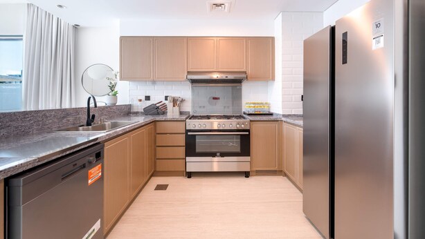 Una cocina moderna con armarios de madera, un refrigerador de acero inoxidable y un horno empotrado.
