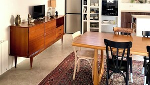 Een moderne keuken met een houten plafond, een eethoek met een getextureerd vloerkleed en een ingebouwde boekenkast.