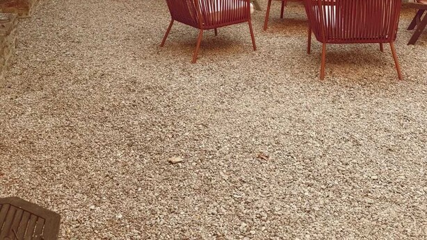 Een terras met rieten meubels, een stenen muur en een deur.