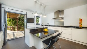 Cocina moderna con una isla central, comedor con sillas y vistas al exterior.