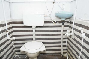 A small, narrow bathroom with a striped tile wall, a white toilet, a white tank, and a light blue sink.