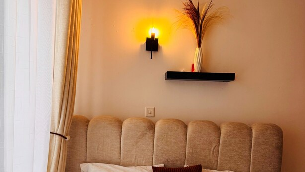 A neatly made bed with a rolled towel, a headboard with a light fixture, and a shelf with a vase. - 1Bedroom 1Bath | Perfect for Couples & Business (Nairobi)
