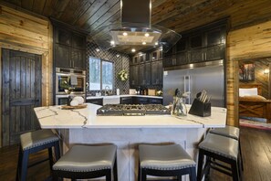 Una cocina moderna con una isla central, electrodomésticos de acero inoxidable y un interior rústico de madera.