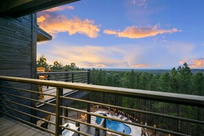Une terrasse en bois avec une piscine et des chaises longues, offrant une vue sur un paysage boisé.