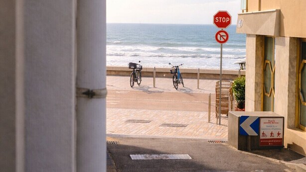 Eine Küstenstraße mit einem Stoppschild, Fahrrädern und einem Gebäude mit einem Balkon.