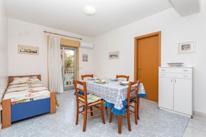 Un dormitorio con una cama, una mesa de comedor con sillas, un armario y una puerta.