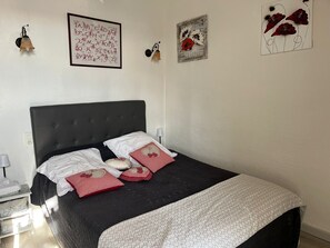 Een slaapkamer met een donker hoofdbord, witte beddengoed en decoratieve kussens.
