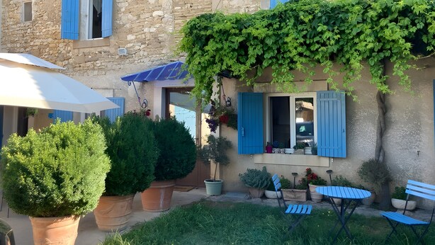 A stone building with blue shutters, a covered patio, and potted plants. - Bed and Breakfast 'Mas De Maussan' with Mountain View, Wi-Fi and Air Conditioning (Robion)