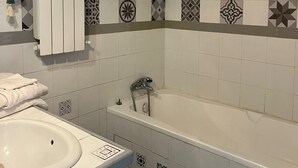 A bathroom with a bathtub, a sink, and a towel rack. - Bed and Breakfast 'Mas De Maussan' with Mountain View, Wi-Fi and Air Conditioning (Robion)