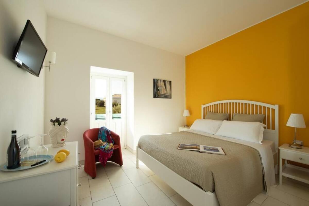 Um quarto com uma cama, mesas de cabeceira, televisão e janela.