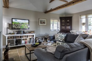 Ein Wohnzimmer mit Fernseher, Sofa, Couchtisch und Bücherregal.