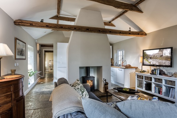The open-plan living space with exposed beams and a wood burning stove