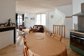 Amplia sala de estar con una mesa de comedor, un sofá y una escalera que sube a otro nivel.