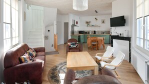 Uma sala de estar com sofá, mesa de centro e um espaço de jantar com cadeiras.