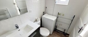 Un bagno piccolo e bianco con lavandino, water e portasciugamani.