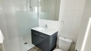 Een badkamer met een wit wastafel, donker kastje en toilet.