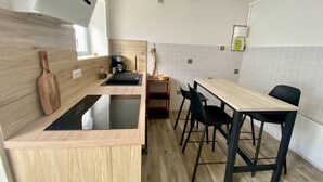 Een compacte keuken met een houten aanrecht, een spoelbak, een koffiezetapparaat en een klein zite hoekje met twee stoelen.