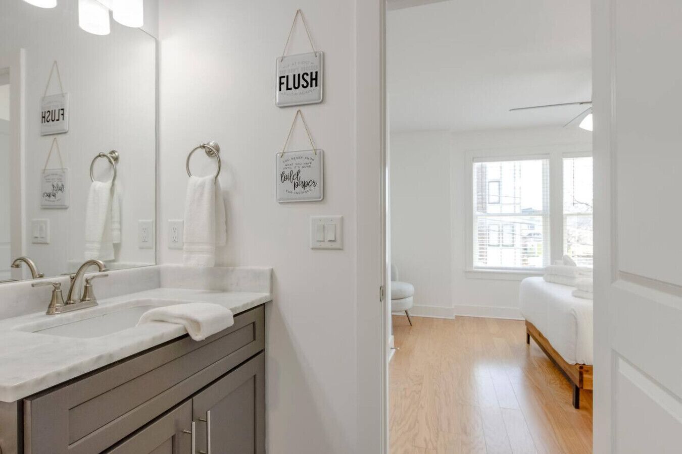 Un baño moderno con un espejo grande, dos lavamanos y un cartel de papel higiénico.