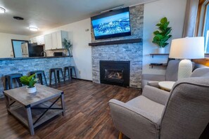 A modern living room with a stone fireplace, a flat-screen TV, and a comfortable seating area. - 2 King Bed Charming Mountain Retreat Close to Mtn (Steamboat Springs)