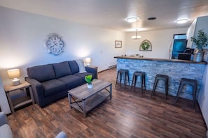 A modern living room with a dark sofa, a wooden coffee table, and a stone accent wall. - 2 King Bed Charming Mountain Retreat Close to Mtn (Steamboat Springs)
