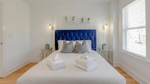 A bedroom with a large bed, a wooden ceiling fan, and a window with blinds.