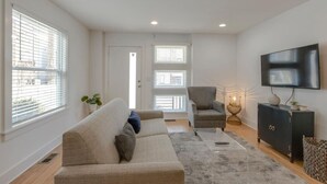 A modern living room with a sofa, armchair, and a TV on a stand.