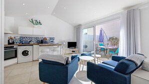 Una cucina moderna con elettrodomestici, una zona pranzo con sedie, un divano e vista sull'esterno.