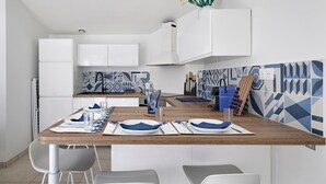 Una cucina moderna con mobili bianchi, un tavolo da pranzo in legno apparecchiato per due persone e uno schienale con motivi geometrici.