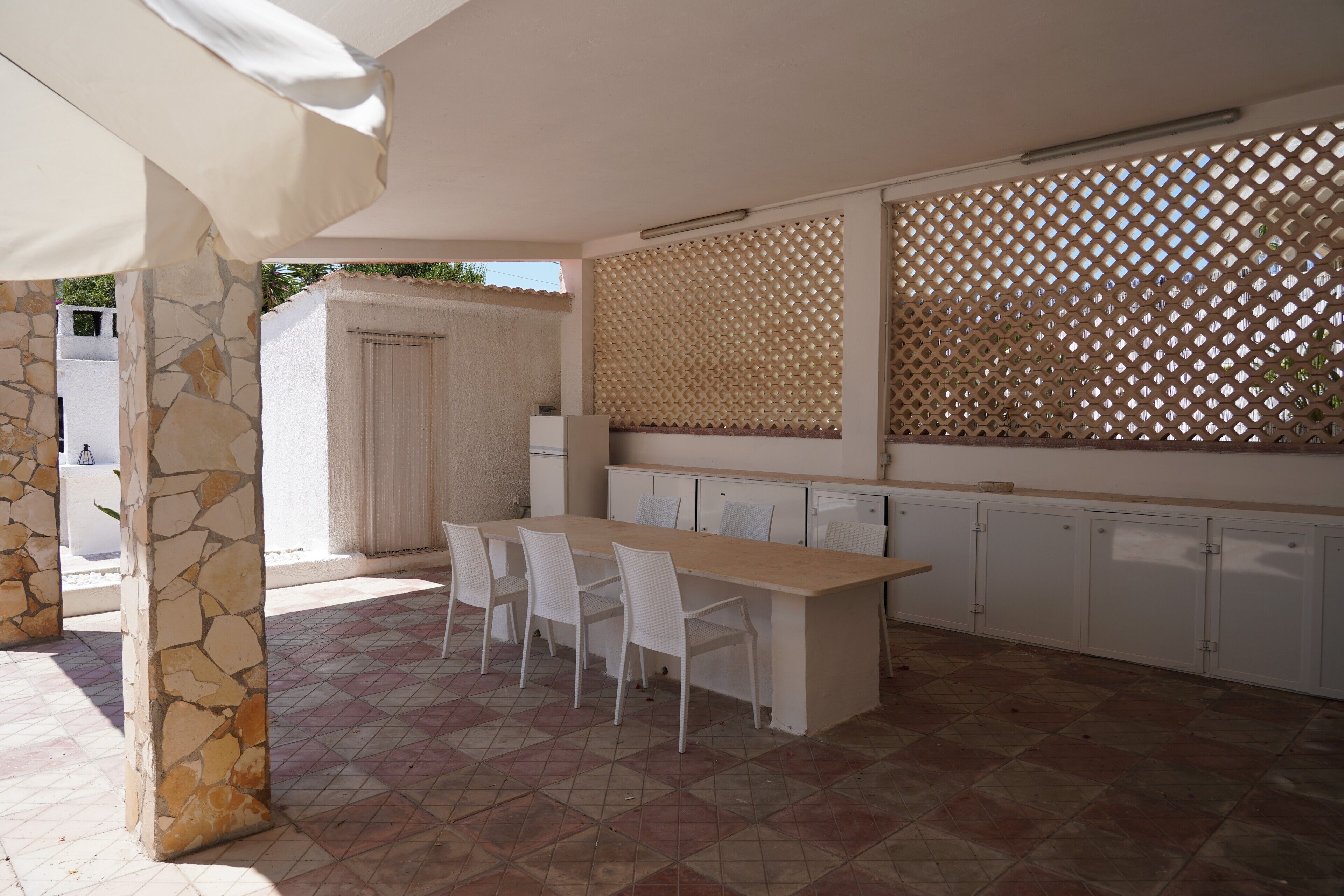 A kitchen with a stone column, white chairs, a wooden table, and white cabinets.
