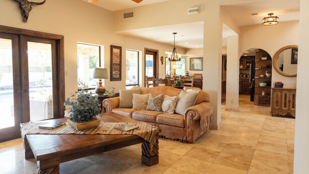 A spacious living room with a large sofa, a wooden coffee table, and a ceiling fan.