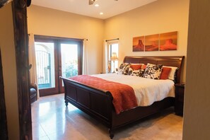 A bedroom with a large bed, a nightstand, a lamp, and a view of the outdoors through a sliding door. - The Bradford - Southwest Luxury w/ Pool + Mountain Views in Sunny Fountain Hills (Fountain Hills)