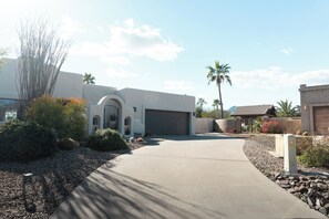 A modern house with a garage, a driveway, and a landscaped garden with rocks and plants. - The Bradford - Southwest Luxury w/ Pool + Mountain Views in Sunny Fountain Hills (Fountain Hills)