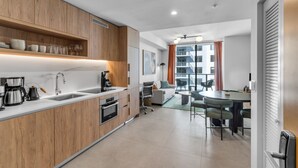 Een moderne keuken met houten kastjes, een ingebouwde oven en een koffiehoek.