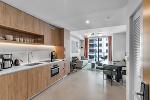 A modern kitchen with wooden cabinets, a built-in oven, and a coffee station. - Stylish Urban 1BR Downtown Rooftop Pool & Views (Miami)