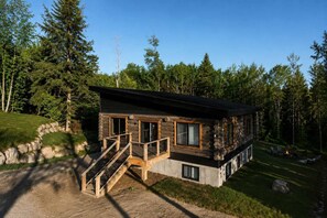 Une cabane en rondins dotée d’une terrasse, d’un escalier et d’un espace aménagé pour faire un feu de camp.