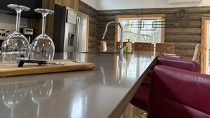 Ett modernt kök med en stor köksö, rostfria vitvaror och en vägg med träpanel som ger en snygg accent.