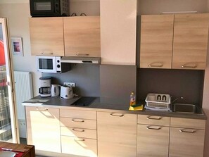 A compact kitchen with a microwave, toaster, and coffee maker on the countertop. - Apartment Am Yachthafen auf Fehmarn (Fehmarn)