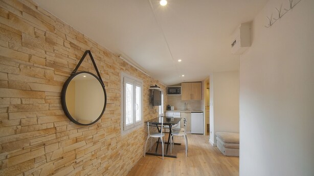 A modern kitchen with a stone wall, a round mirror, and a dining area with a table and chairs. - Cannes hyper center historic district of suquet-palais du festival - Croisette (Cannes)