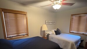A bedroom with two beds, a ceiling fan, and a wall sign. - Lake home with beautiful views, private sandy beach, great location. (Alexandria)