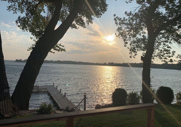 A lakeside view with a dock extending into the water, surrounded by trees.