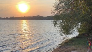 A wooden deck leading to beach chairs facing a lake at sunset. - Lake home with beautiful views, private sandy beach, great location. (Alexandria)