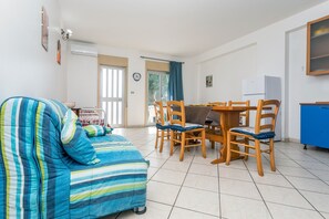 Ein Zimmer mit einem gestreiften Sofa, einem Holzespeiseplatz, Stühlen, einem Kühlschrank und einem blauen Schrank.