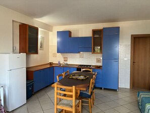 Een koelkast, een kookplaat, kookgerei, borden en bestek